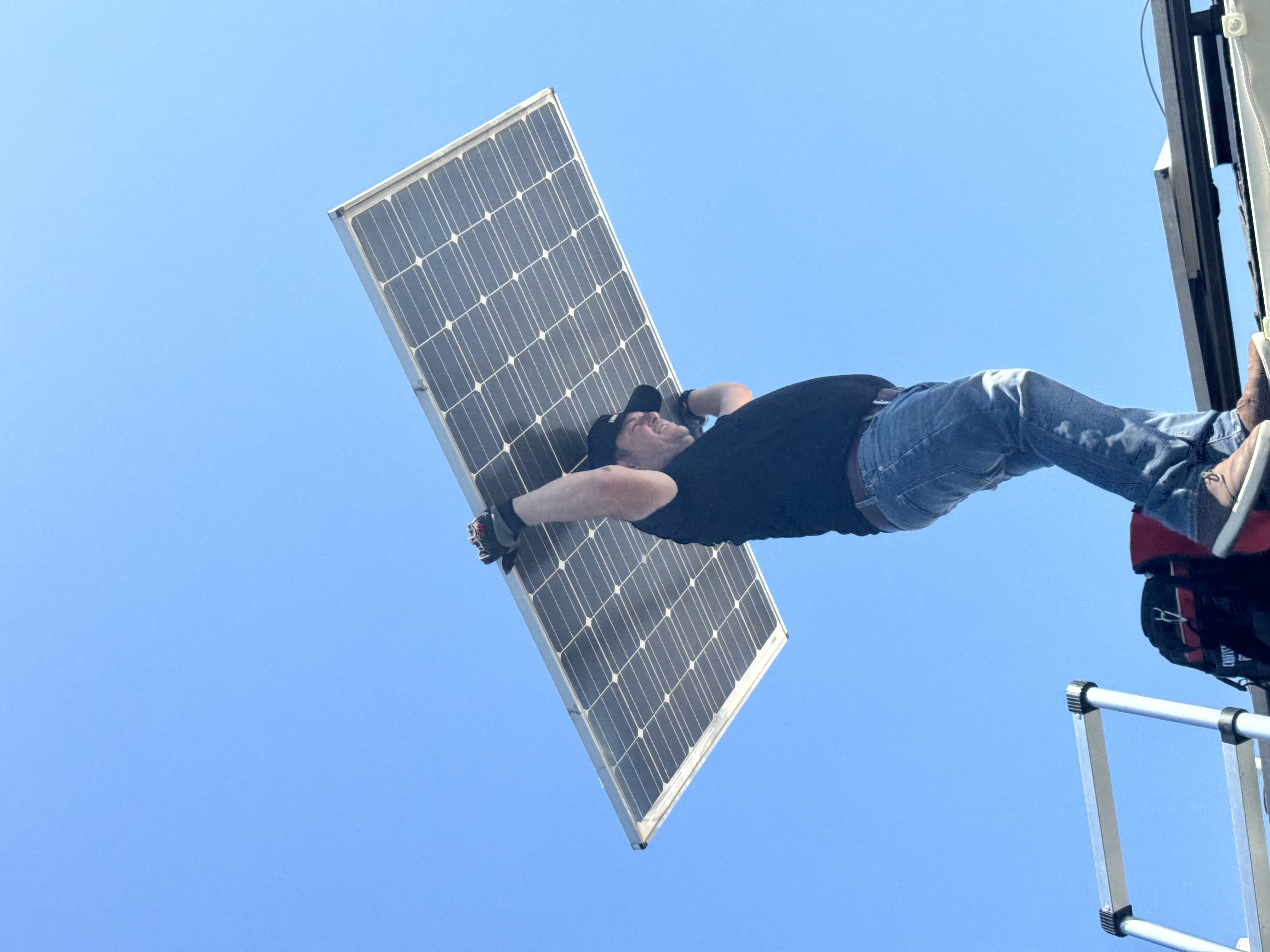Installer carrying solar panel up ladder